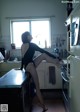 A woman sitting on top of a kitchen counter next to a refrigerator.