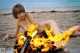 A naked woman laying on the beach next to a fire.