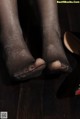 A close up of a woman's legs in black stockings and high heels.