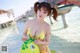 A woman in a yellow bikini holding a yellow toy turtle.