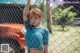 A woman standing in front of a chain link fence.