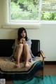 A woman sitting on a couch holding a cup of coffee.