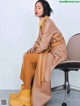 A woman sitting on a chair wearing yellow rain boots.