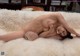 A naked woman laying on top of a white rug.