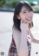 A young woman in a plaid dress smiles at the camera.