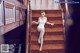 A woman in a white bodysuit is sitting on the stairs.