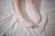 A pair of white lace socks and gloves on a bed.