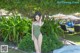 A woman in a green bathing suit standing next to a pool.