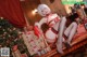 A woman in a red lingerie sitting on a couch next to a Christmas tree.