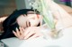 A woman laying on a table next to a vase of flowers.